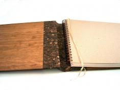 Libro con tapas de madera, lomera en corcho y cinta registro en rafia.  	